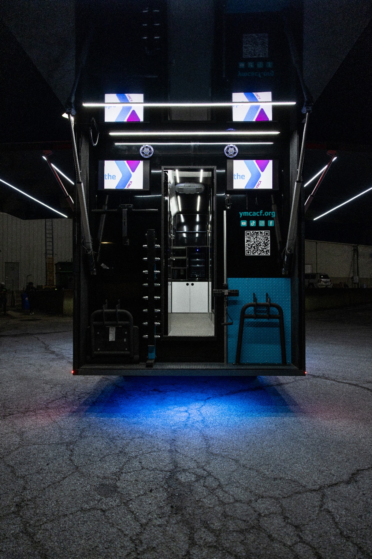 Open rear of the YMCA Fit Truk with illuminated displays and an interior doorway