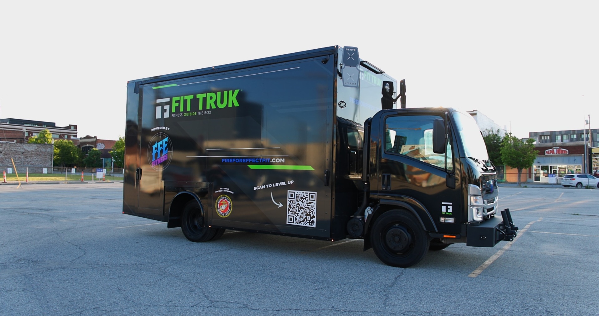 FFE Fit Truk 2.0 closed for transit, carrying the Fit Truk wordmark, Powered by FFE Fitness, fireforeffectfit.com, a scan-to-level-up QR code, a U.S. Marine Corps veteran-owned emblem and a CENTR x HYROX beacon